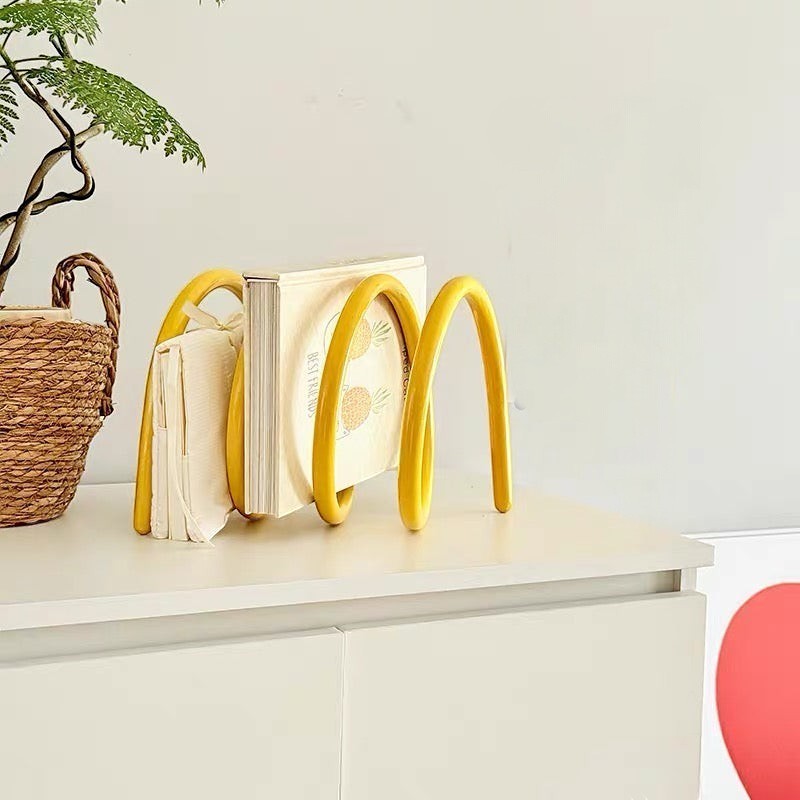 HOMELIVY yellow retro spiral book holder with a wave design holding books on a white surface.