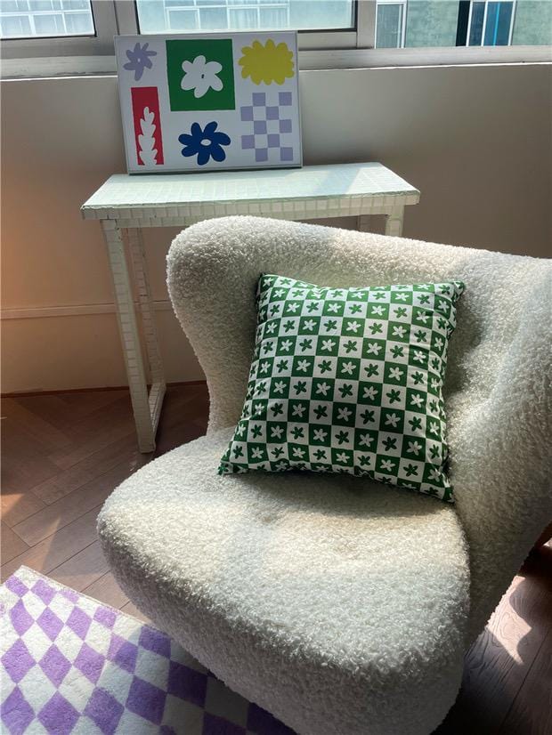 Green and white floral checkered throw pillow case with geometric design on plush cream-colored armchair
