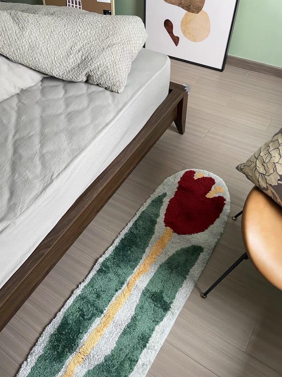 A plush rectangular red rose flower rug with a vibrant red tulip green leaves and yellow stem on a soft white background