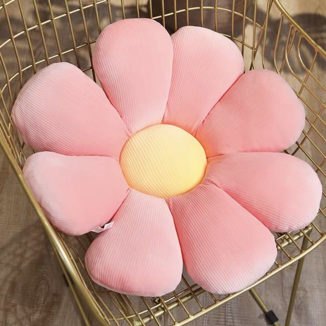 Pastel flower cushion is a pink corduroy flower-shaped cushion with a yellow center on a gold wire chair