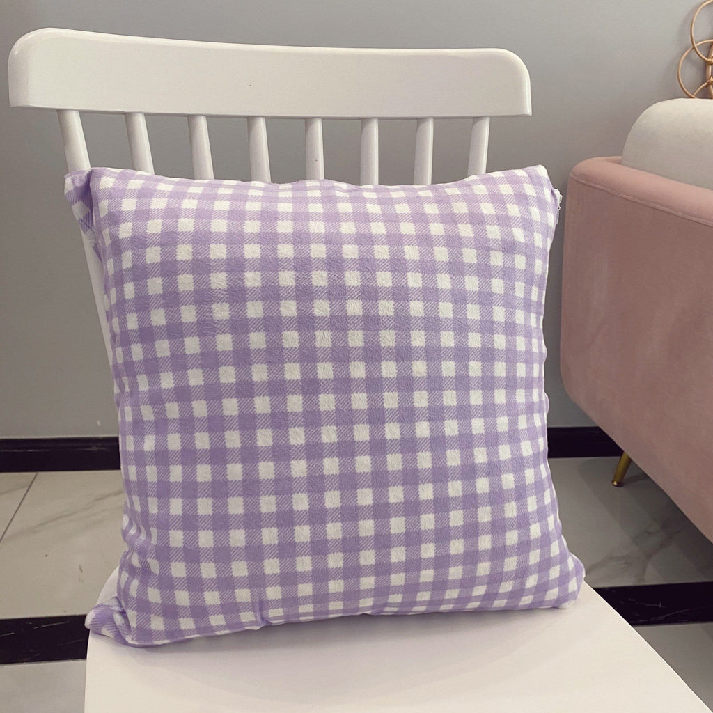 Pastel purple gingham plaid throw pillow with soft lavender and white pattern resting on a white chair