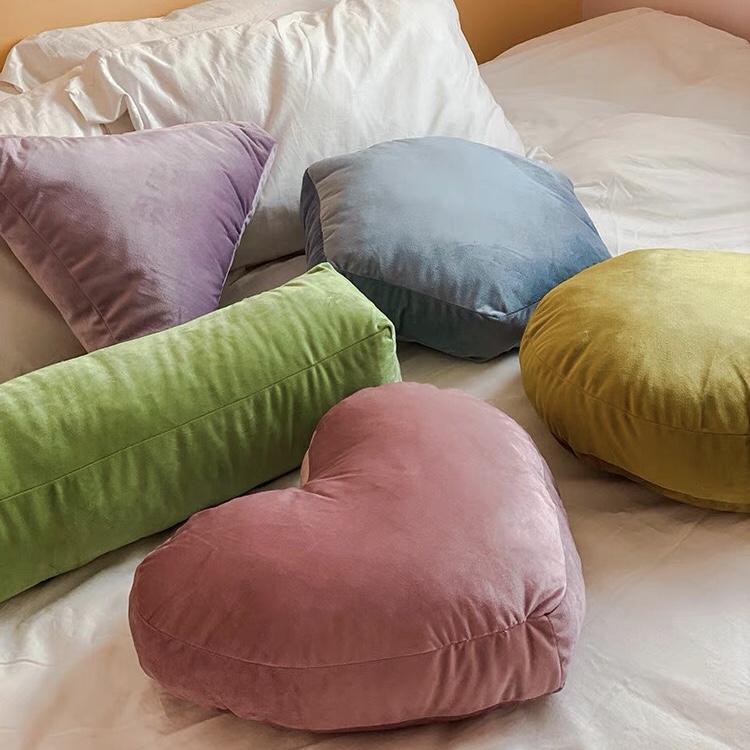 A plush velvet geometry pillow in dusty rose shaped like a heart with a soft velvet texture